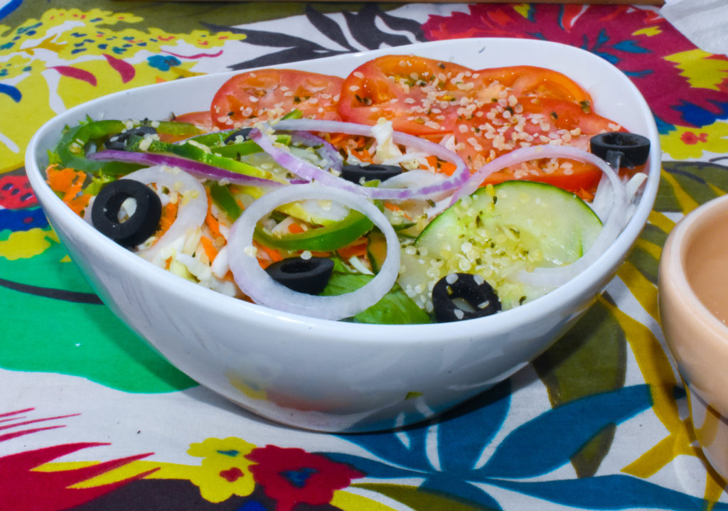 Healthy island food salad recipe with tomatoes, black olives, onions, sweet peppers, lettuce and hemp seeds at Caribbean restaurant, Tropical Blendz Cafe, a tropical island cafe
