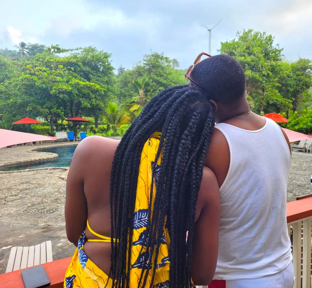 Black girl and caribbean boy on black sand beach wearing yellow silk ankara Ngaska print at 
at luxury caribbean resort, Dominica