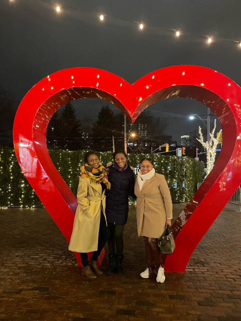 Friends around a red heart at the distillery christmas market in Toronto 2022