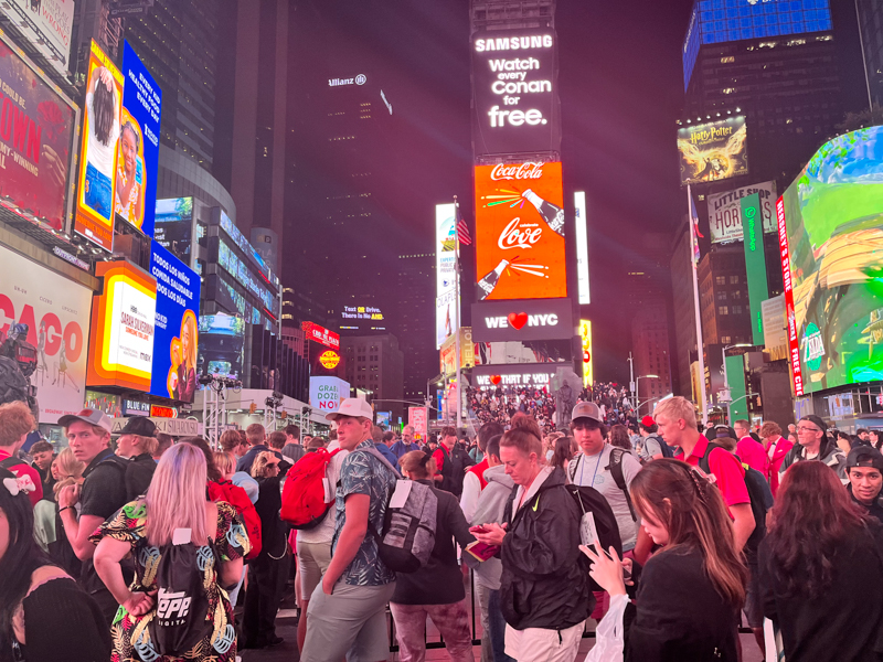 People crossing the road and walking through New York City Time Square at Night