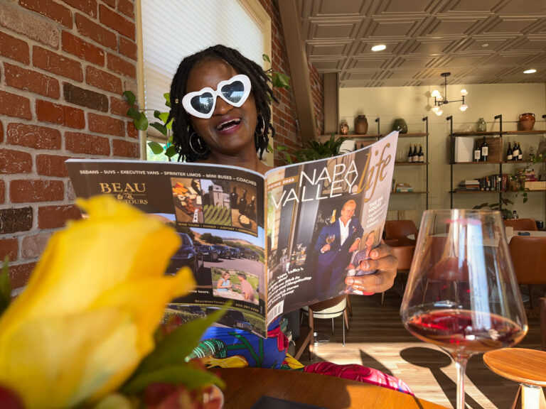 Tasting room downtown Napa: Travel with Clem posing with a Napa valley magazine, seating at the New Frontiers Co Wine Tasting Room