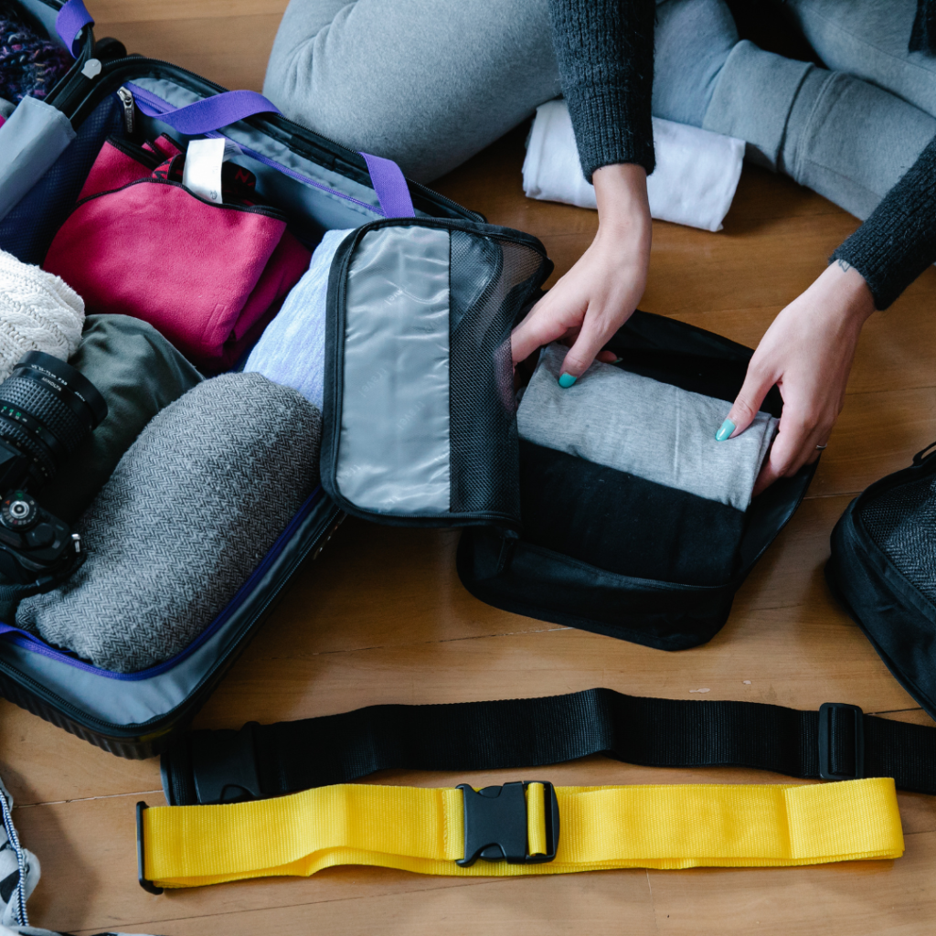 How to Pack Your Suitcase to Maximize Space - white girl packing in packing cubes and small containers. Grey outfits and grey suitcases