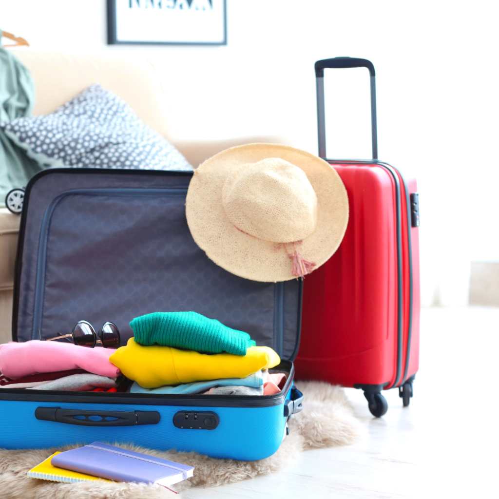 How to Pack Your Suitcase to Maximize Space - suitcase packed with a vacation hat and a red carryon