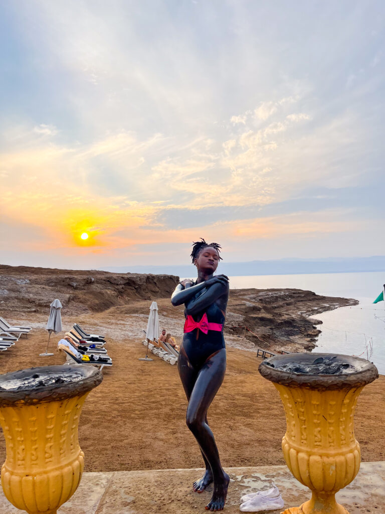 Floating in the dead sea: Tourist applying mineral-rich mud on arms and face