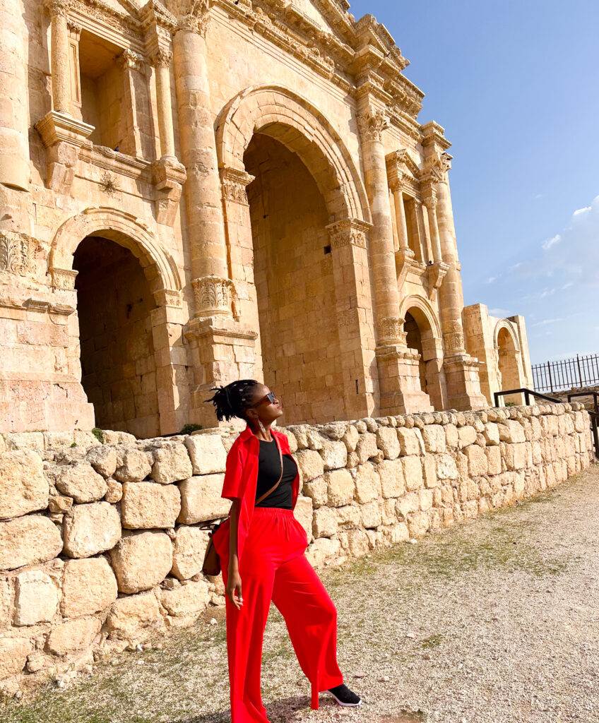 Jordan travel visa - everything you need to know before visiting - Travel with Clem posing in an orange top and bottom suit during a cultural tour in the ancient ruins of Jerash