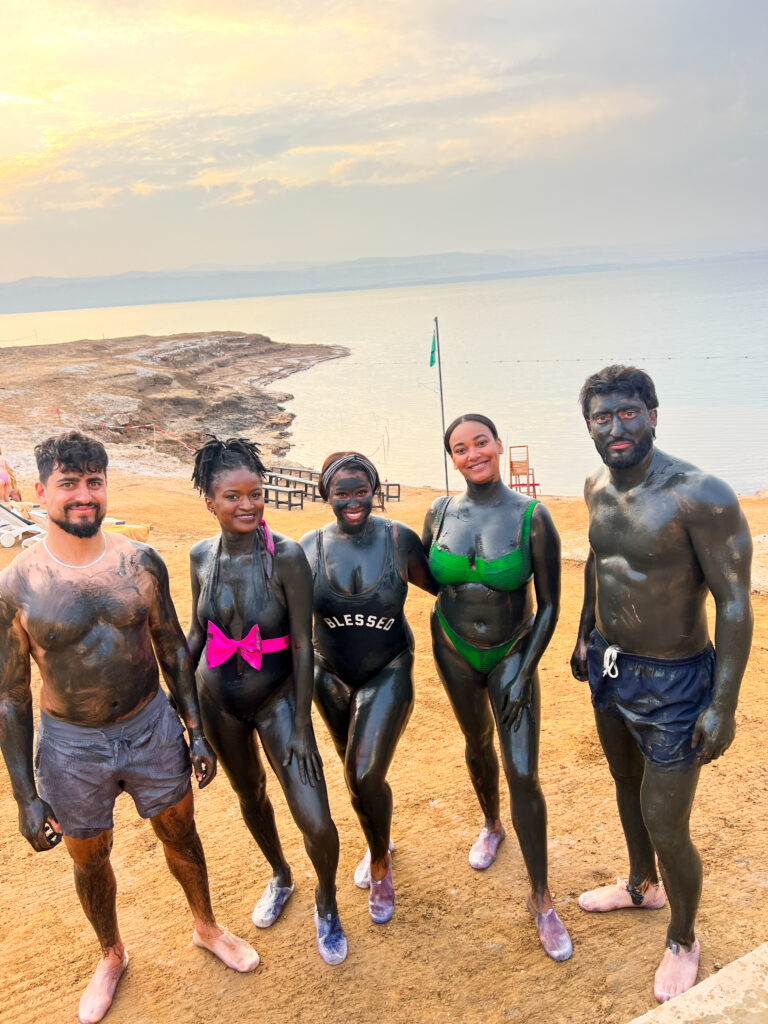 Travel with Clem and other travel creators and influencers posing at the Dead Sea after having applied a Dead Sea Mud Mask 