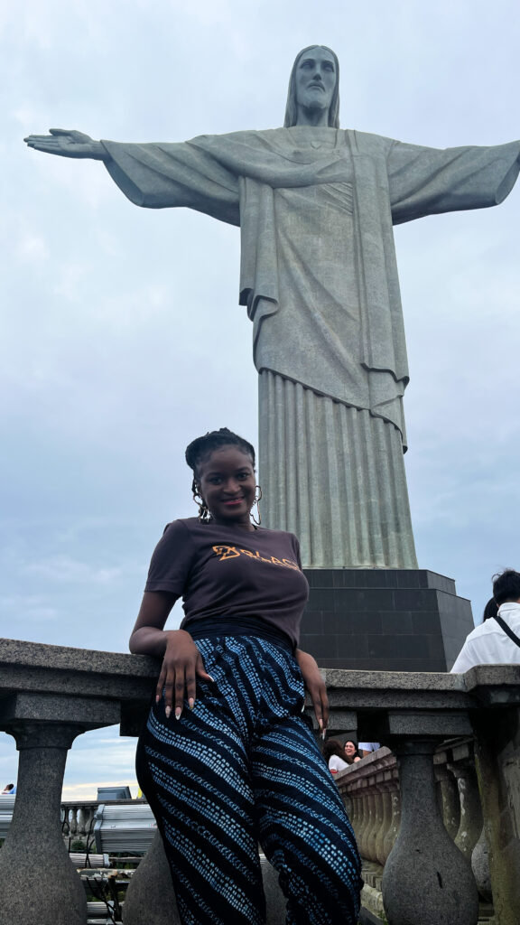 Travel with Clem (Clementine Affana) posing in front of the statue while visiting Christ the Redeemer